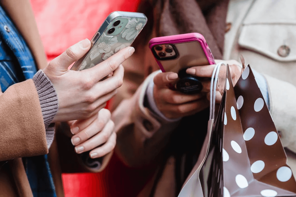 two people holding smartphones while shopping